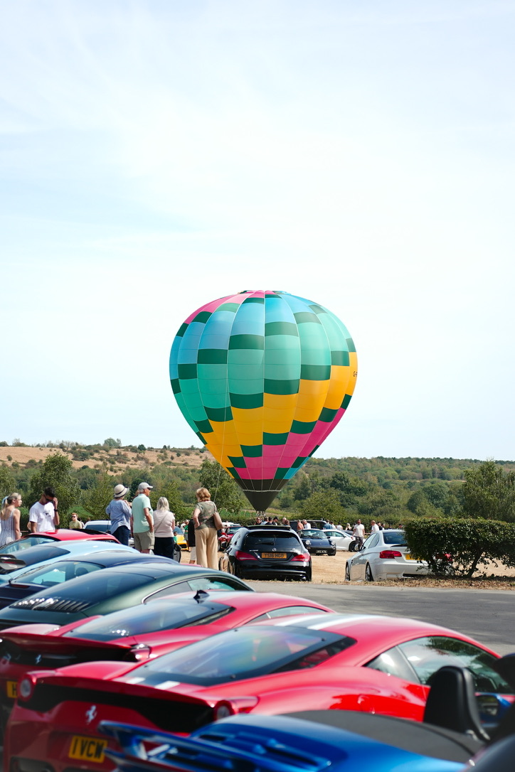 Hot air balloon behind a row of Ferraris